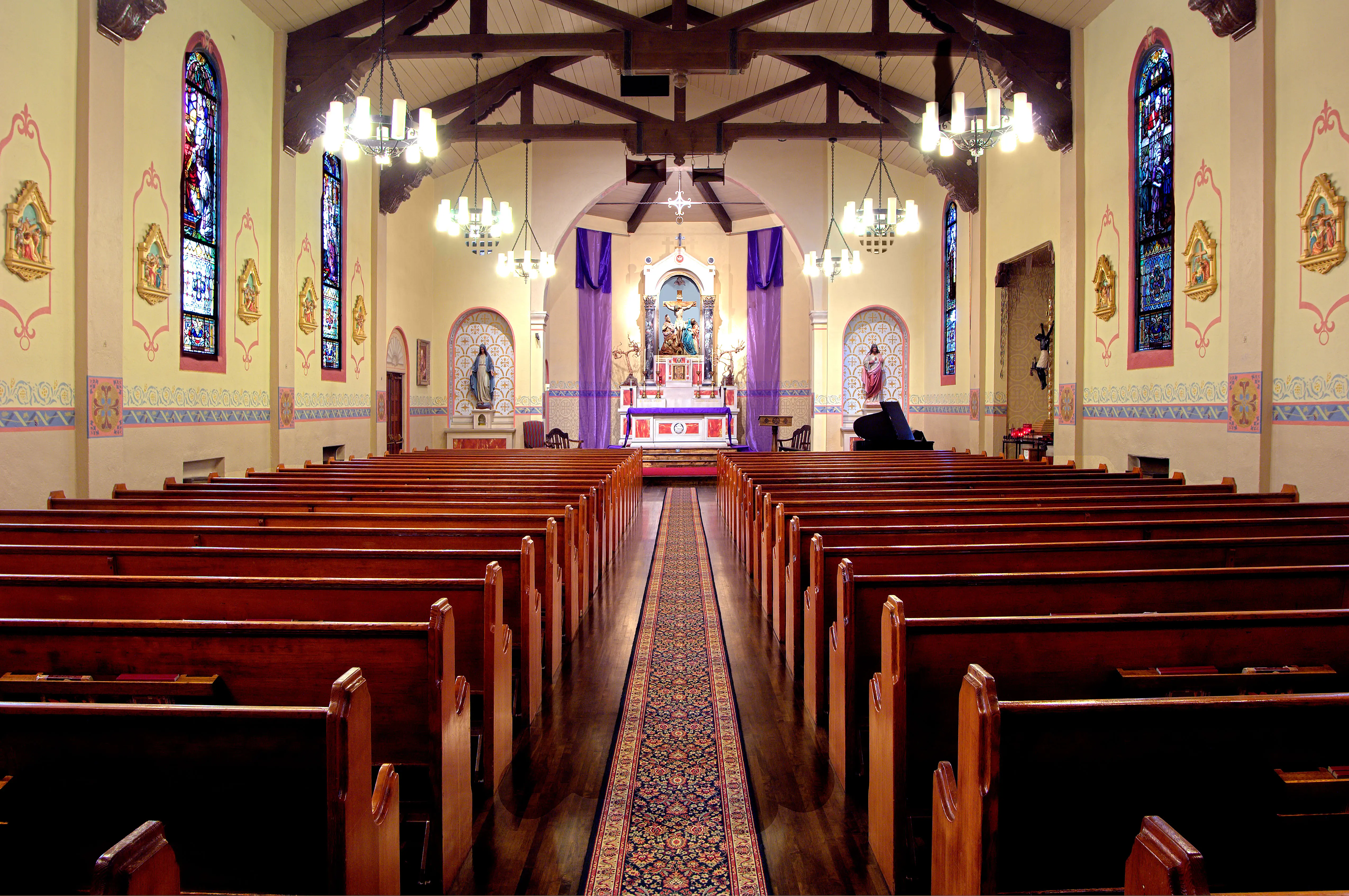 Nave of Holy Spirit Parish looking towards the sanctuary, with stencilled wall borders, painted window surrounds and a decorated reredos