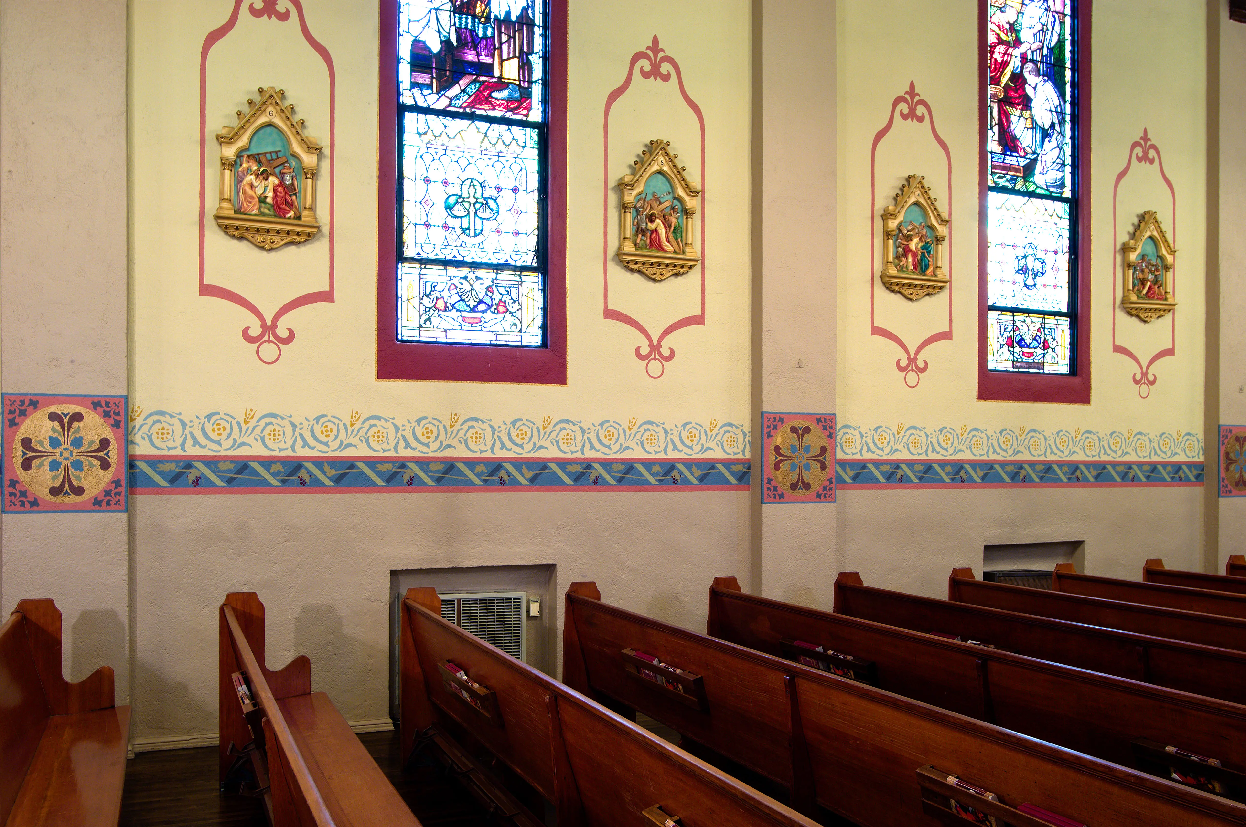 Hand-cut stencilled decorative border in blue, rose and gold on a plastered church wall